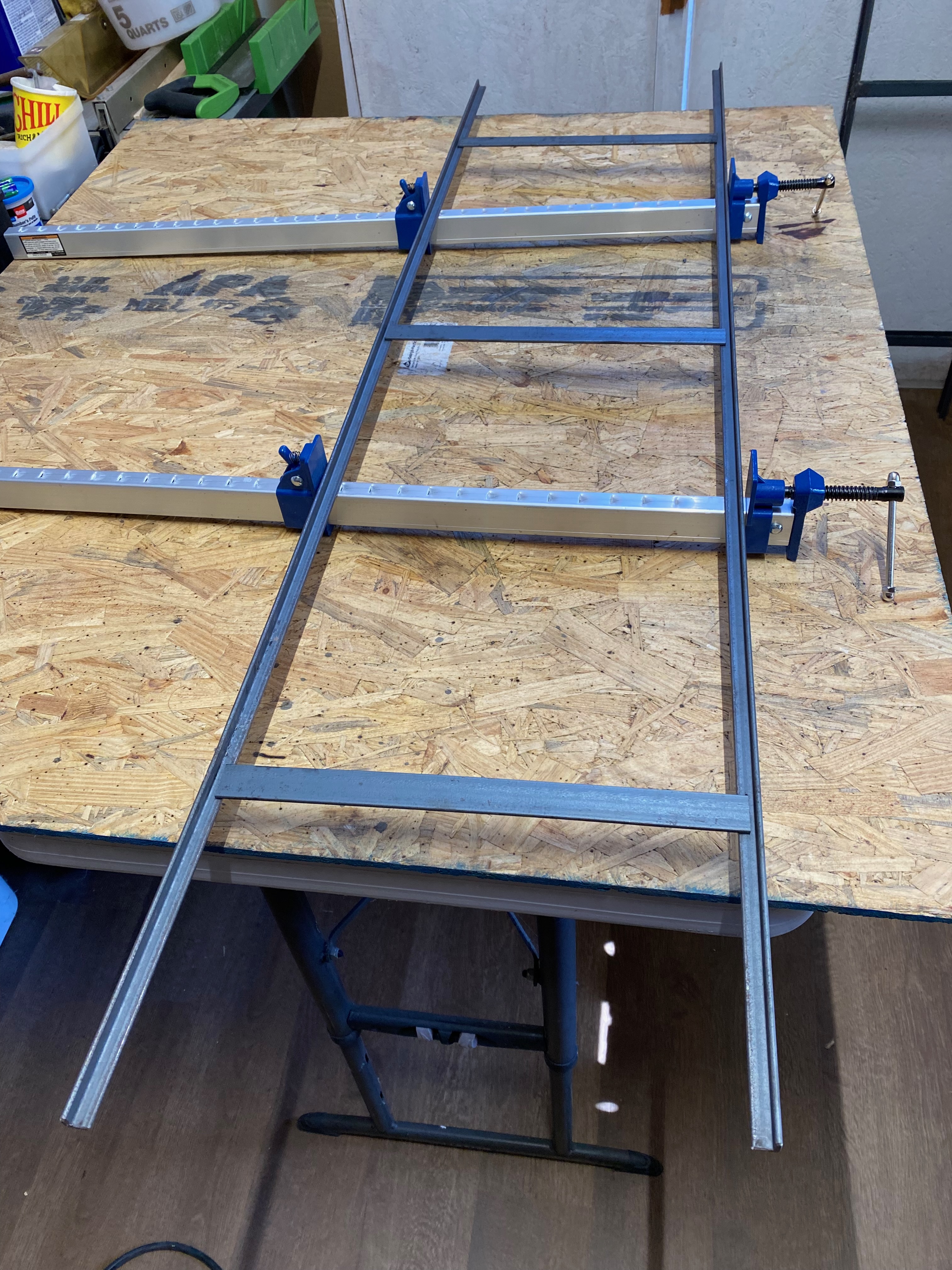 Raw steel frame squared with clamps and hardboard jig.